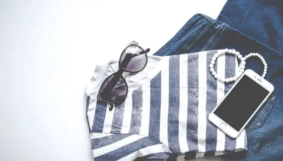 striped tshirt folded with sunglasses and bracelet on top