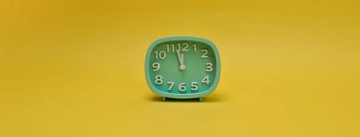 small teal anaolgue clock against a yellow background